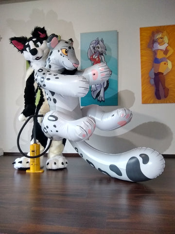 Border collie (fursuiter) holding up a Lizet design snep in one arm while pumping it up with a handpump with the other arm.